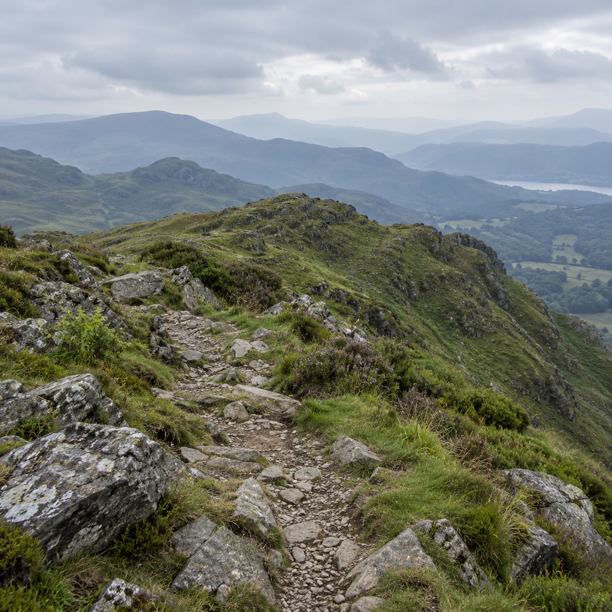 A rocky hiking path with blue grey mountain ridges in the distance